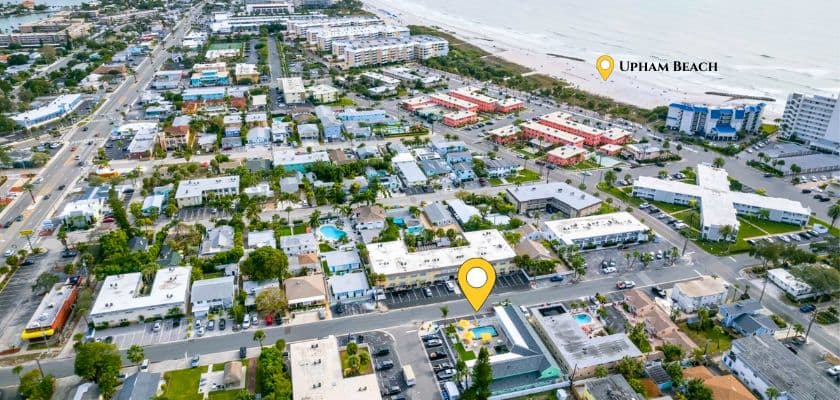 Aerial view of a coastal area showing roads, buildings, and a marker for Upham Beach.