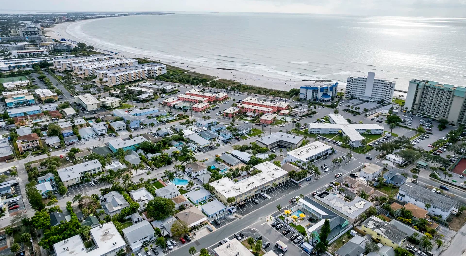 Aerial view of a coastal town with a beach and various residential buildings.